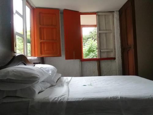 a bedroom with a bed and two windows at Cabaña rural con piscina in Manizales