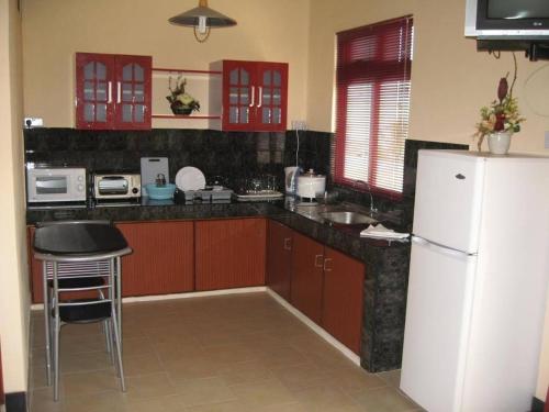 a kitchen with red cabinets and a white refrigerator at Les Studios De Grand Baie in Grand Baie