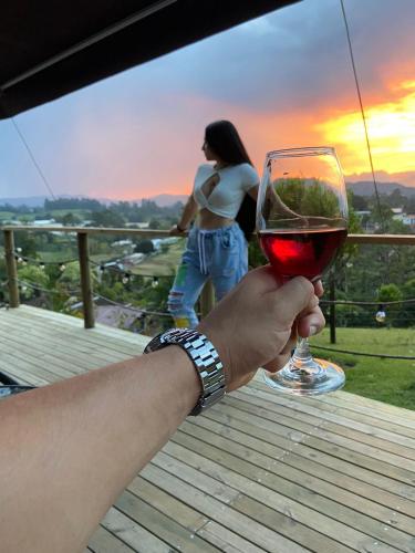 a hand holding a glass of wine with a woman at Glamping Carmen de Viboral in Carmen de Viboral