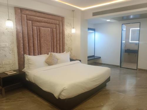 贾巴尔普尔HOTEL KADAMB TREE的卧室里有一张白色的大床和一面镜子