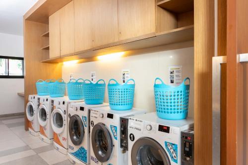 a laundry room with four washing machines and blue baskets at Holiday Inn Express Phuket Patong Beach Central by IHG in Patong Beach