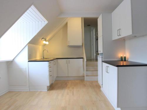 an attic kitchen with white cabinets and a staircase at 6 person holiday home in Svaneke in Svaneke