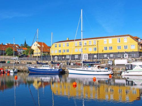 un grupo de barcos atracados en un puerto con un edificio amarillo en 3 person holiday home in Svaneke, en Svaneke