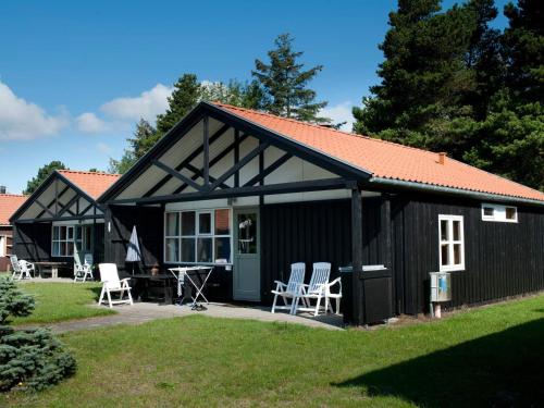 een zwart huisje met witte stoelen in de tuin bij 6 person holiday home on a holiday park in V ggerl se in Bøtø By