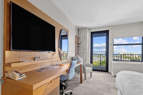 a hotel room with a desk with a large television at Four Points by Sheraton Punta Gorda Harborside in Punta Gorda