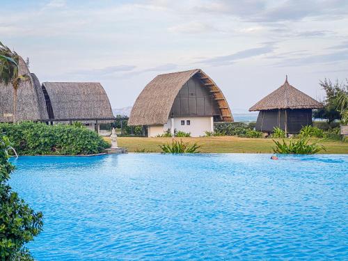 un complejo con piscina y 2 edificios con techo de paja en Muine Bay Resort, en Mui Ne