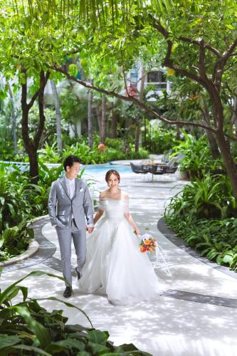 a bride and groom walking down a path at Chatrium Sathon Bangkok in Bangkok