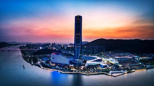 a tall building in the middle of the water at sunset at The St. Regis Zhuhai in Zhuhai
