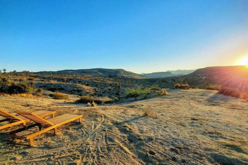 a bench sitting on top of a hill with the sunset at Pipe's Perch in Yucca Valley