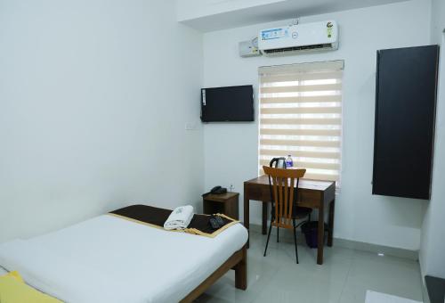 a bedroom with a desk and a bed and a table at AIRPORT COCHIN ROYAL RESIDENCY in Ernakulam