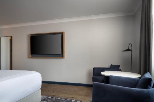 a hotel room with a bed and a tv on the wall at Edinburgh Marriott Hotel Holyrood in Edinburgh