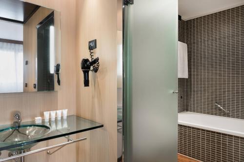 ein Badezimmer mit einem Glaswaschbecken und einer Dusche in der Unterkunft AC Hotel Bologna by Marriott in Bologna