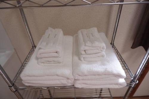 un toallero con toallas blancas. en TSUBAME 101 staying private home en Osaka