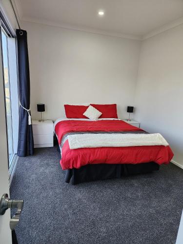 a bedroom with a red bed and a window at Oasis Rural Retreat in Norsewood