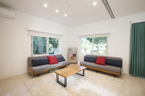 ein Wohnzimmer mit 2 Sofas und einem Couchtisch in der Unterkunft アイニクル -Create Future Community- in Ishigaki-jima