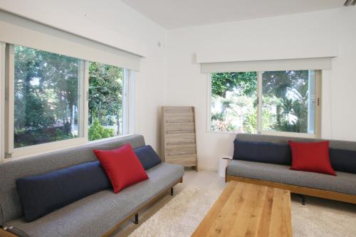 ein Wohnzimmer mit 2 Sofas und 2 Fenstern in der Unterkunft アイニクル -Create Future Community- in Ishigaki-jima
