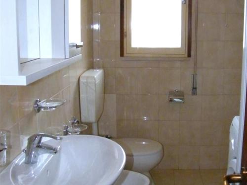 a bathroom with a sink and a toilet and a window at Cosy apartment with balcony in Porto Santa Margherita di Caorle