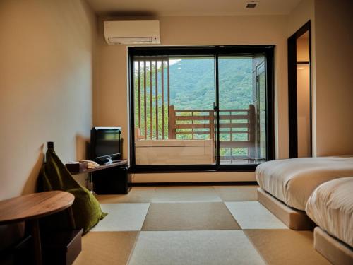 a bedroom with a bed and a view of a balcony at Hatago Kintoen in Hakone