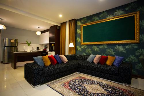 a living room with a black couch with colorful pillows at Nagawari Art Maldives BBQ Pattaya Villa in Na Jomtien