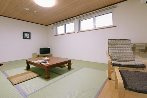 a living room with a table and a chair at Pension Ashitaya in Furano