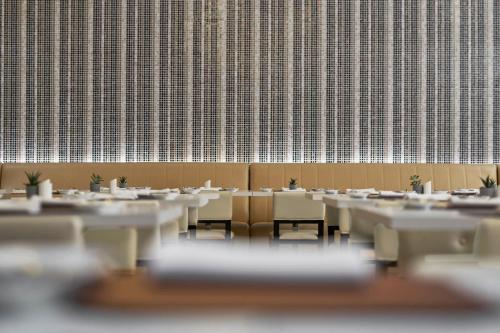a row of tables and chairs in a room with a wall at AC Hotel by Marriott Penang in Bayan Lepas