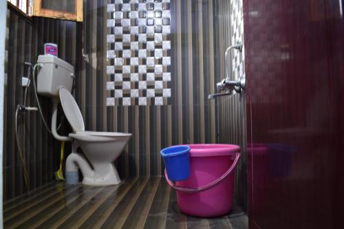 a bathroom with a toilet and a bucket at Rainbow Guest House in Tiruvannāmalai