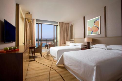 a hotel room with two beds and a television at Sheraton Bailuhu Resort, Huizhou in Huizhou