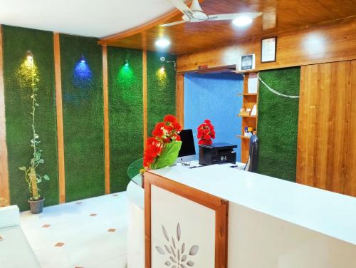 an office with a green wall and a desk with flowers at Balaji Hotel in Ahmedabad