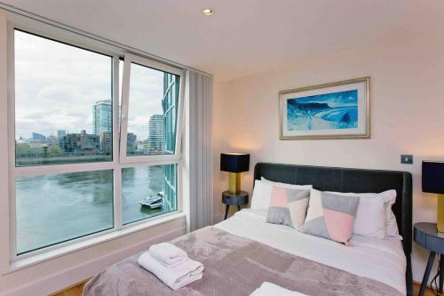 Schlafzimmer mit einem Bett und einem großen Fenster in der Unterkunft Lovely 2BD flat with River view in London
