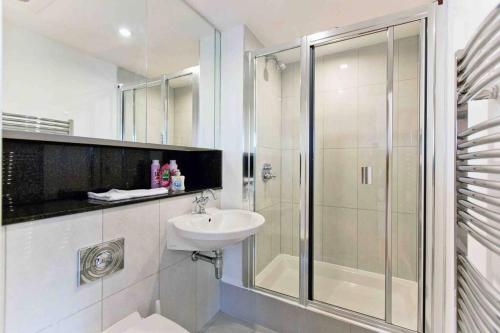 biała łazienka z prysznicem i umywalką w obiekcie Lovely 2BD flat with River view w Londynie