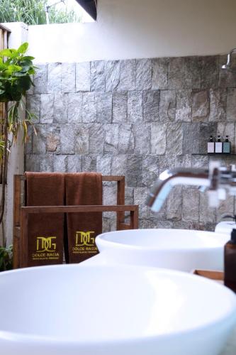 a bathroom with a sink and a stone wall at Dolce Magia in Gili Trawangan