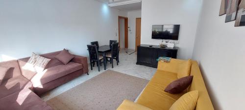 uma sala de estar com um sofá e uma televisão em Oméga em El Aouina