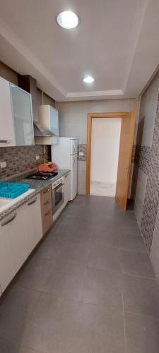 a large kitchen with white cabinets and a door at Oméga in El Aouina