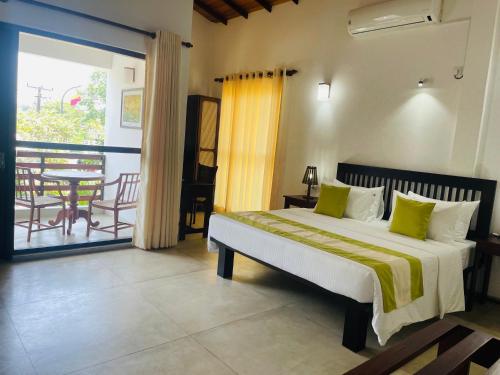 a bedroom with a bed and a balcony with a table at THE Mangrove cave Hotel in Balapitiya