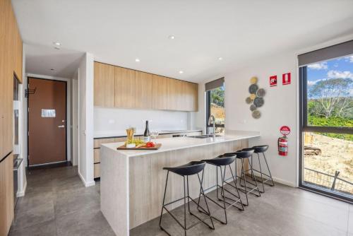 a kitchen with a counter and bar stools at Chilam B in Jindabyne