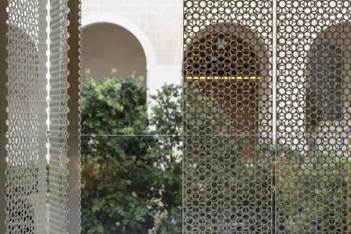 a view through a metal fence with trees in the background at The Jaffa - Fattal Limited Edition in Tel Aviv