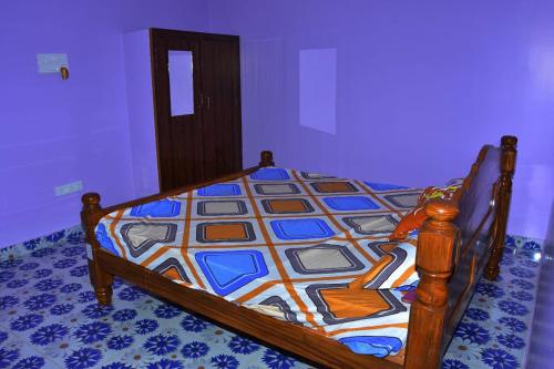 um quarto com uma cama de madeira e uma colcha colorida em Re leaf Resort em Auroville