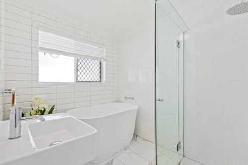 a white bathroom with a tub and a shower at Broadbeach Waterfront home with pool in Gold Coast