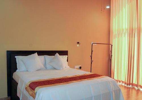 a bedroom with a large bed with white pillows at WoodyCrest in Trincomalee
