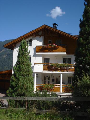 a large white building with a balcony and trees at Haus Venetblick in Wenns
