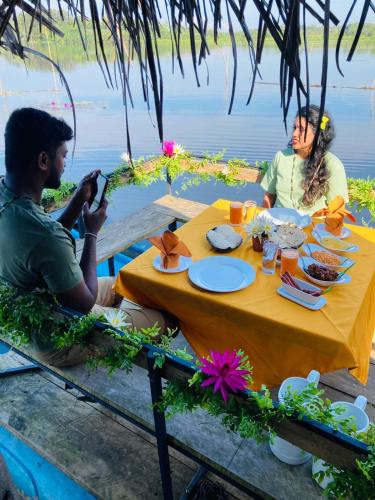 a man and woman sitting at a table with food at Lake Resort Bolgoda in Wadduwa