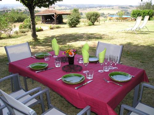 a red table with plates and glasses and flowers on it at Ma Maison sur la Colline in Escosse