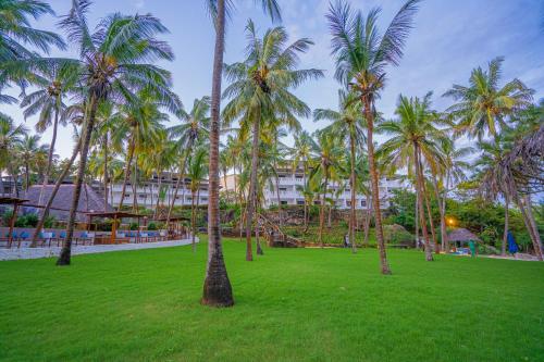 a park with palm trees in front of a building at PrideInn Flamingo Beach Resort & Spa Mombasa in Mombasa