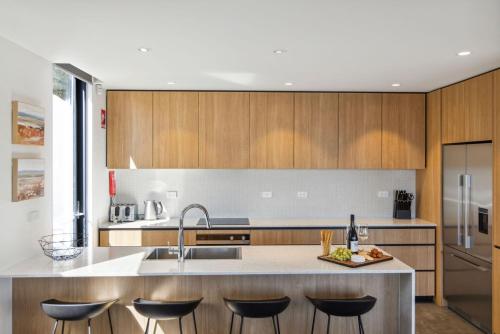 a kitchen with wooden cabinets and a counter with stools at Chilam C in Jindabyne