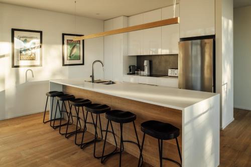 a kitchen with a counter with stools around it at Blessington Beachside Retreat -38km to CBD in South Arm