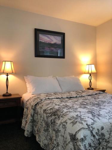 a bedroom with a bed and two lamps on tables at Sun Beach Motel in Osoyoos