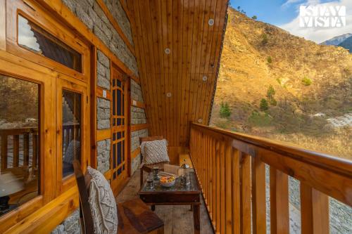 a balcony of a wooden cabin with a table at StayVista at Wisteria Whispers with Bonfire & River View in Gushaini