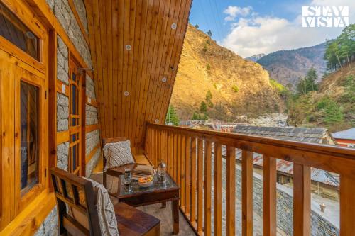 a balcony of a cabin with a table and a view at StayVista at Wisteria Whispers with Bonfire & River View in Gushaini