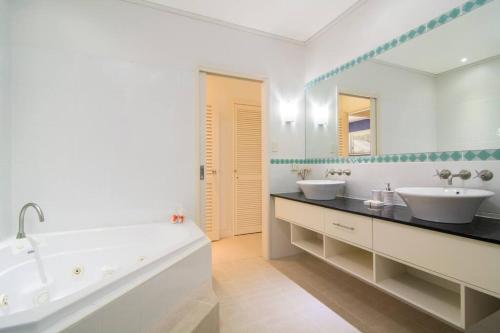 een witte badkamer met 2 wastafels en een bad bij Whispering Palms - Beachfront Port Douglas in Port Douglas