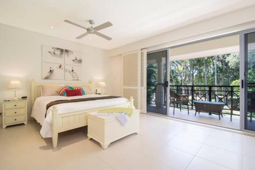 um quarto com uma cama e uma varanda em Whispering Palms - Beachfront Port Douglas em Port Douglas